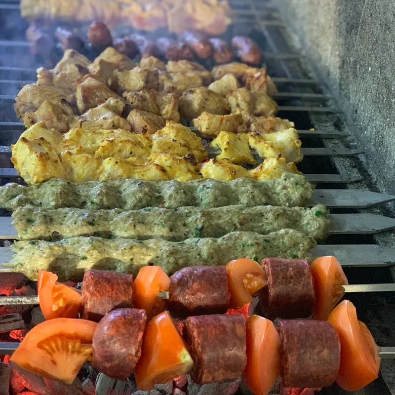 Spett på en grill, kyckling, kött, korv, grönsaker.