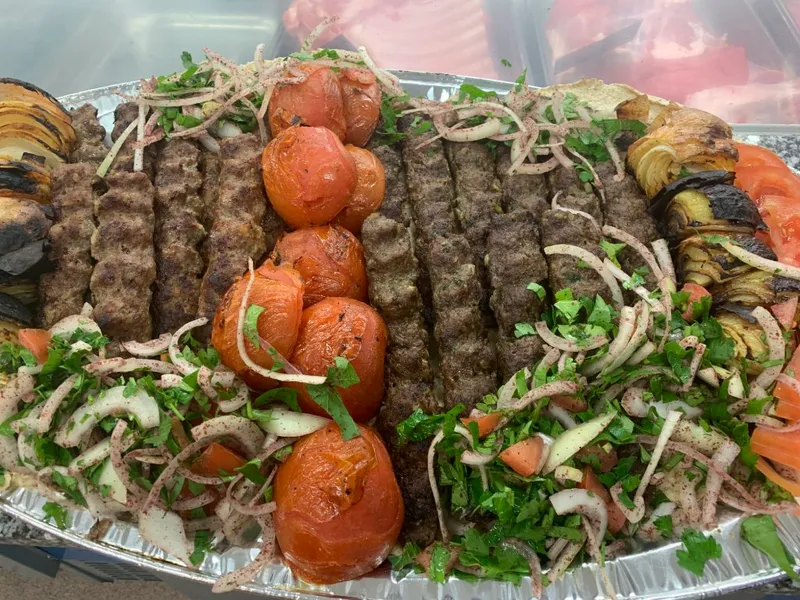Kafta och tomater bland grönsaker på en plåt.
